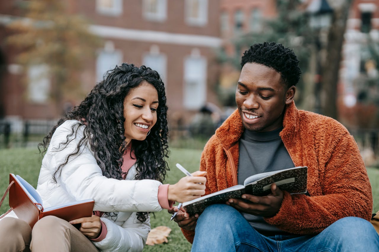 home-hero Happy college students studying together on a campus lawn, sharing ideas and writing notes.
