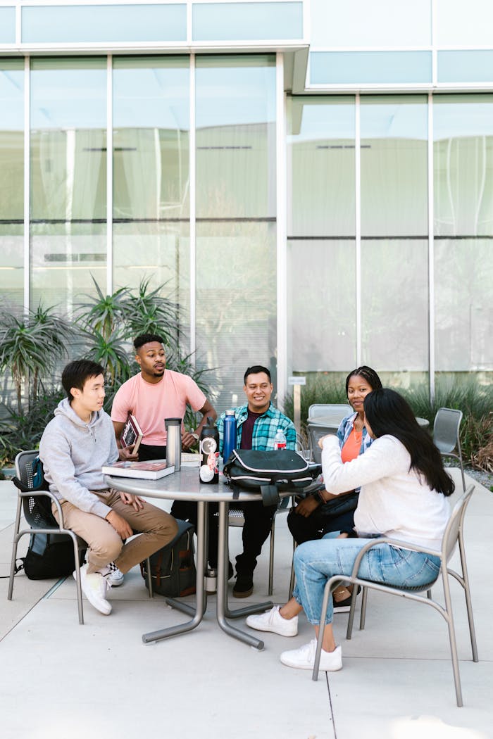 our-story A diverse group of college students studying together outside a modern building.