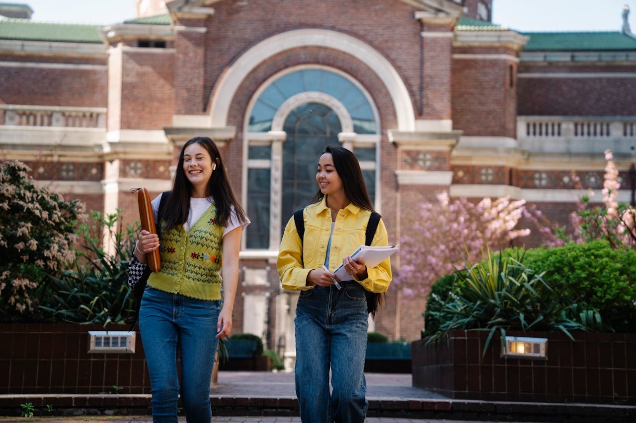 why-choose-us Two smiling young women walk together on a beautiful college campus.