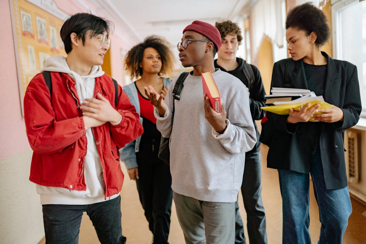 services-03 A group of diverse students walking and talking in a school corridor, carrying books and folders.